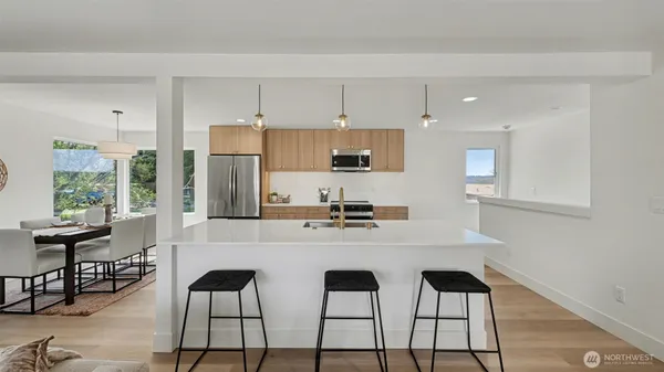 a kitchen with stainless steel appliances kitchen island granite countertop a stove a sink a dining table and chairs