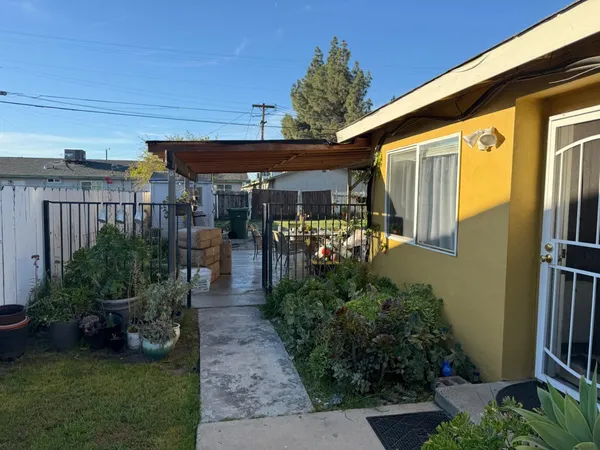 a view of a patio with table and chairs potted plants and floor to ceiling window