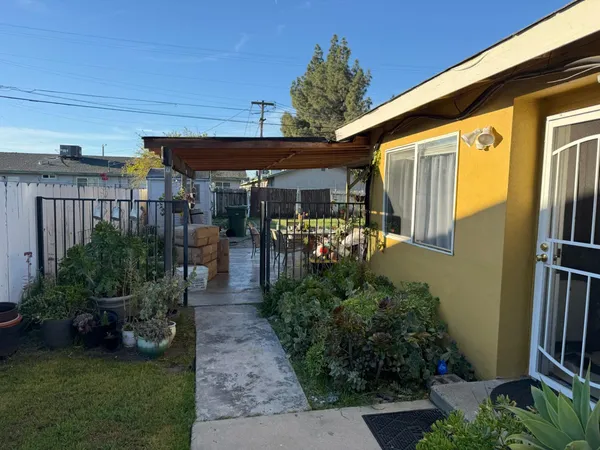 a view of a patio with table and chairs potted plants and floor to ceiling window