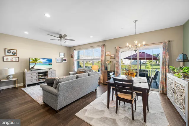 a living room with stainless steel appliances granite countertop furniture wooden floor and a kitchen view