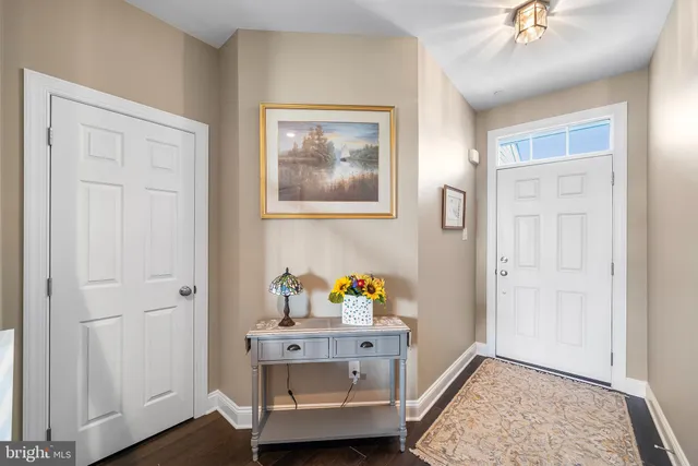 a kitchen with stainless steel appliances granite countertop wooden cabinets a sink a stove a refrigerator and a dining table with wooden floor