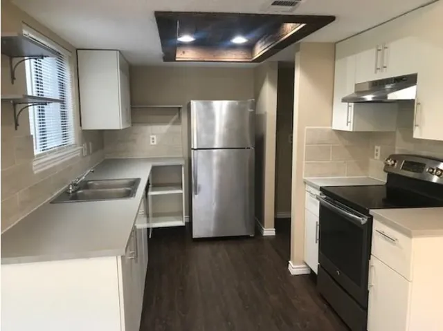 a kitchen with a sink a refrigerator and a stove top oven