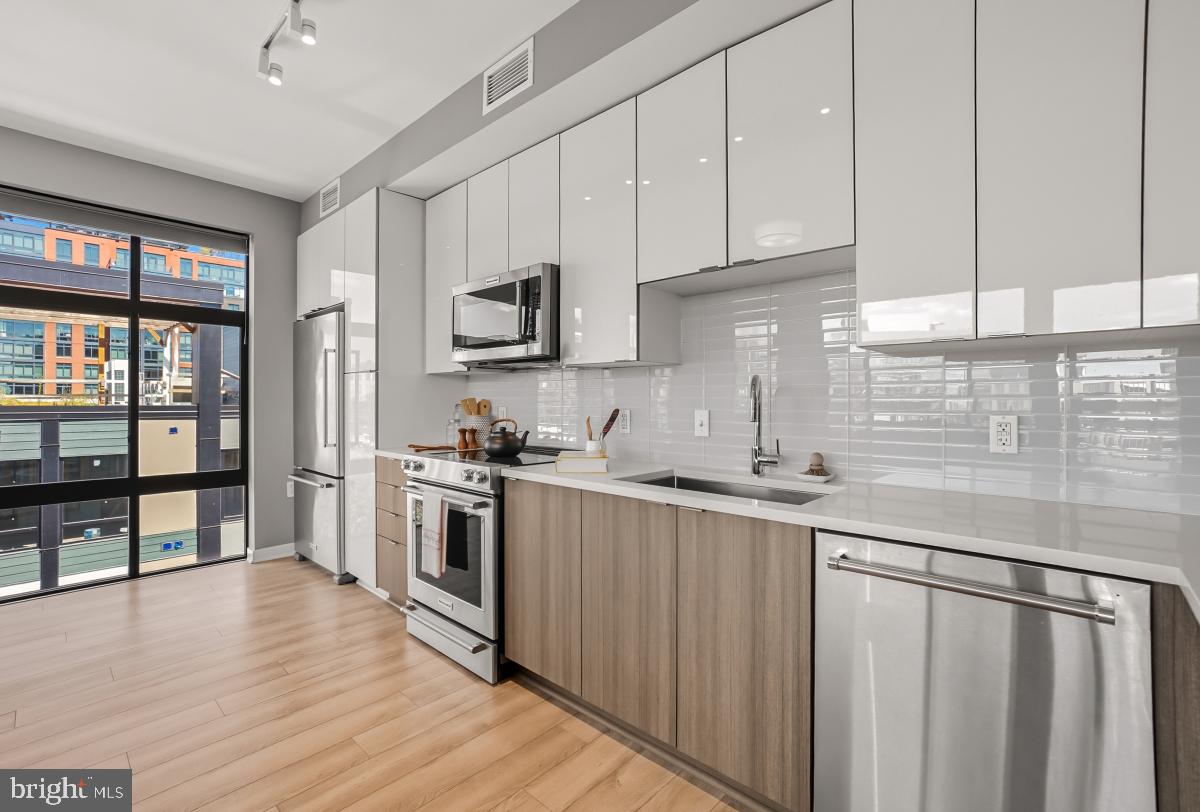 911 2nd Street Northeast, Unit 501 Washington, DC 20002 - Photo 8 of 30 a kitchen with stainless steel appliances granite countertop a stove top oven a sink and white cabinets