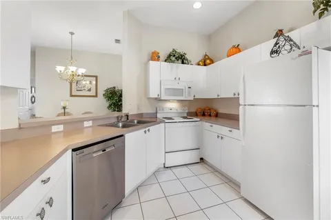 a kitchen with a sink white cabinets and white appliances