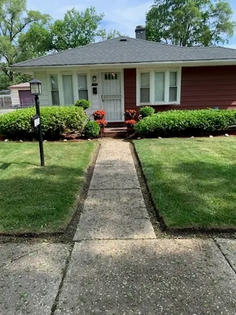 a front view of a house with a yard and potted plants
