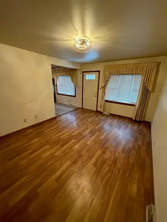 a view of an empty room with a window and wooden floor