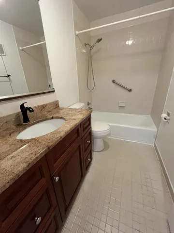 a bathroom with a granite countertop sink a toilet and a bathtub