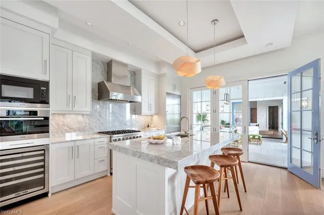 a kitchen with stainless steel appliances granite countertop a stove top oven a sink dishwasher and white cabinets with wooden floor