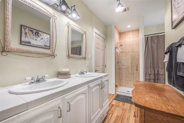 a bathroom with a sink double vanity granite tub shower and a mirror
