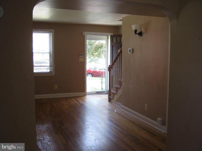 4915 Cedar Garden Road Baltimore, MD 21229 - Photo 3 of 10 an empty room with wooden floor and windows