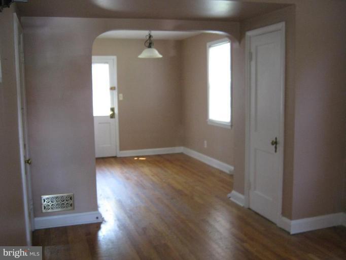 4915 Cedar Garden Road Baltimore, MD 21229 - Photo 4 of 10 an empty room with wooden floor and windows