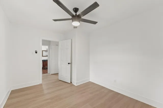 an empty room with wooden floor and ceiling fan