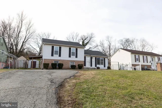 a view of a white house next to a yard with large trees