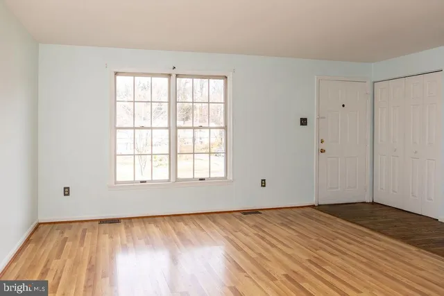 an empty room with wooden floor and windows