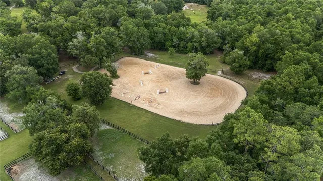an aerial view of a house with pool and trees all around