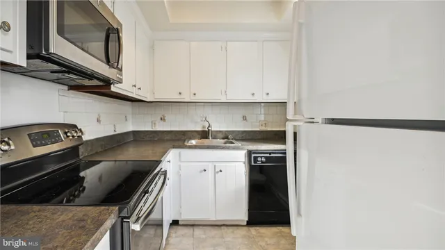 a kitchen with granite countertop white cabinets and a stove