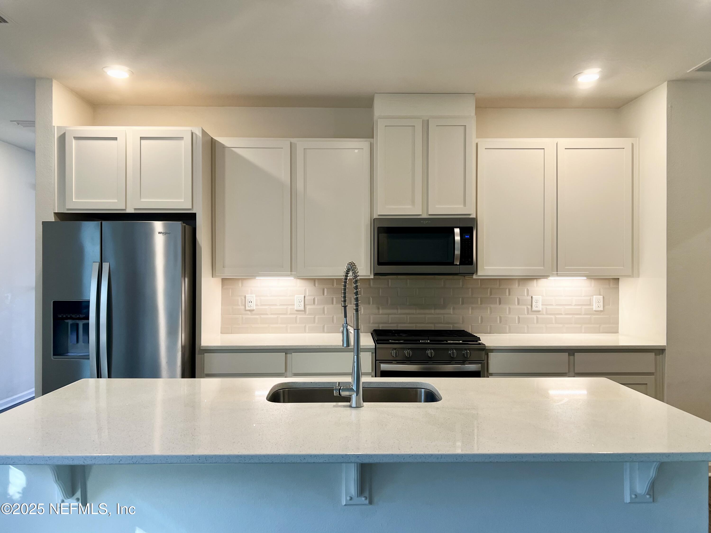 216 Rambling Brk Trail St. Johns, FL 32259 - Photo 5 of 24 a kitchen with kitchen island granite countertop white cabinets and refrigerator