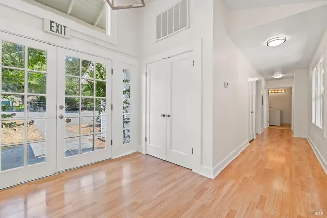 a view of an empty room with chandelier and wooden floor