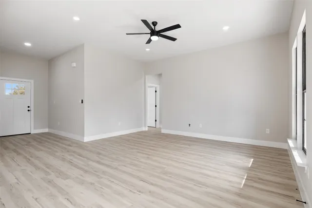 an empty room with wooden floor and ceiling fan