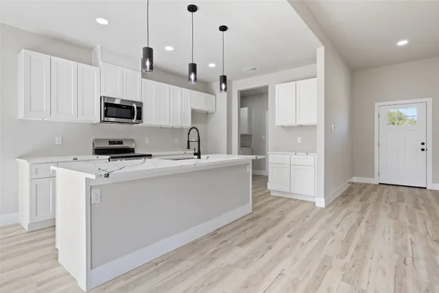 a kitchen with kitchen island a sink a stove and cabinets
