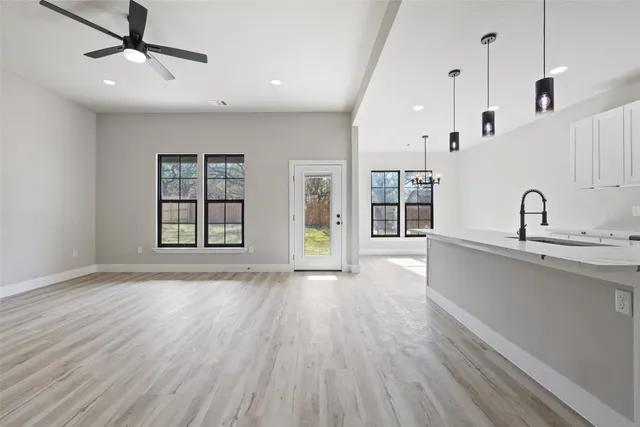 a view of an empty room with window and wooden floor