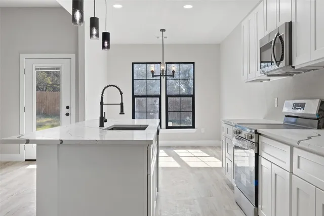 a kitchen with stainless steel appliances granite countertop a stove a sink and a refrigerator with wooden floor