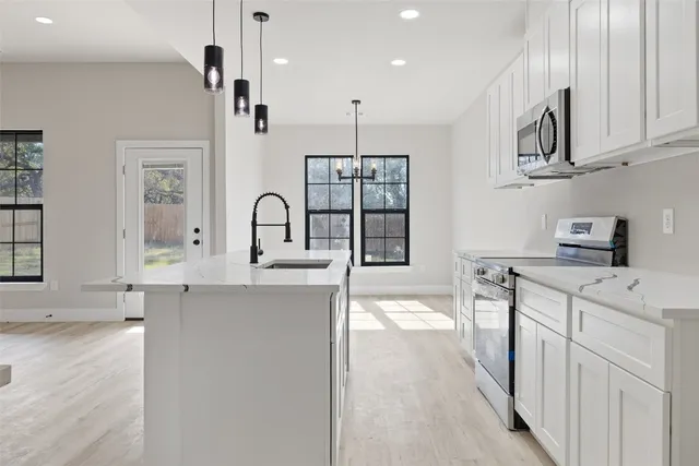 a kitchen with stainless steel appliances granite countertop a sink a stove and a refrigerator