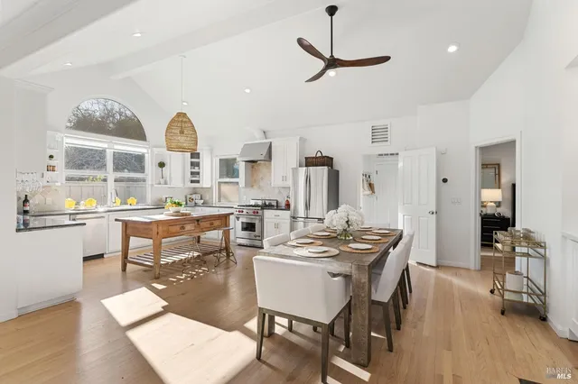 a dining room with wooden floor a chandelier a wooden table and chairs