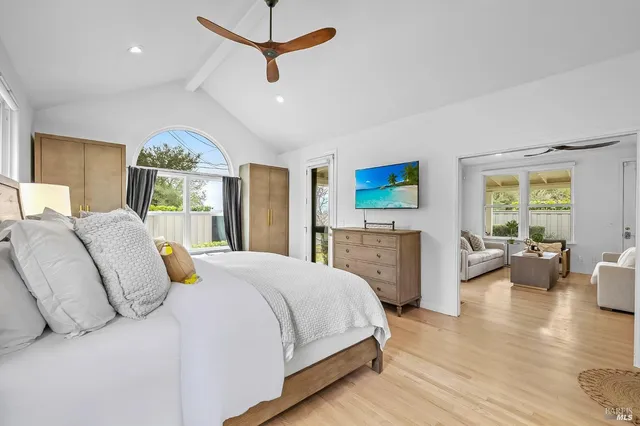 a spacious bedroom with a bed a dresser and a large window