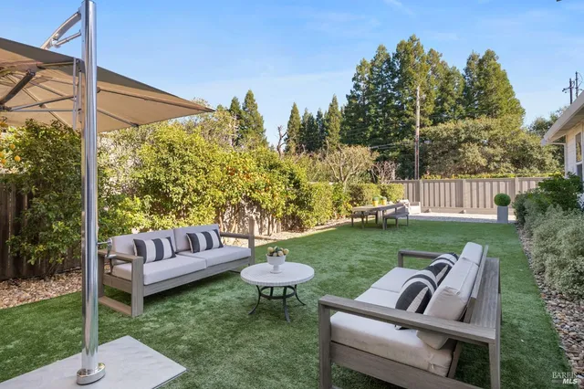 a view of a chair and table in backyard of the house