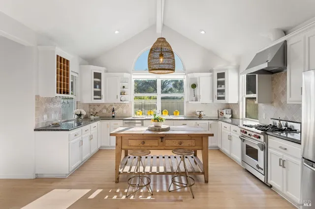 a kitchen with stainless steel appliances a stove a sink dishwasher and white cabinets with wooden floor