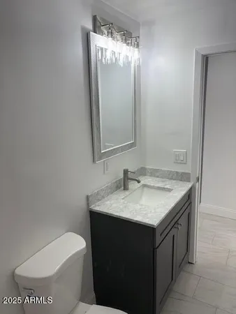 a bathroom with a granite countertop toilet sink and mirror