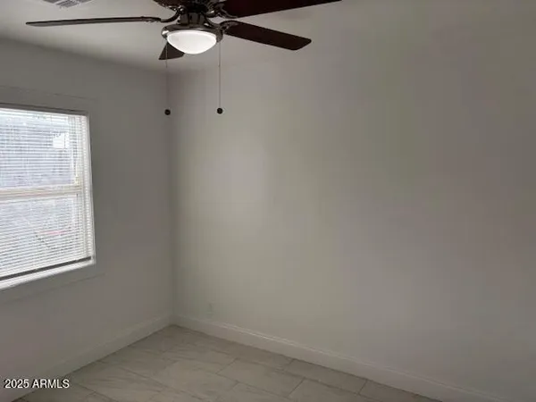 an empty room with a window and a fan