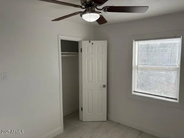 an empty room with a ceiling fan and a window