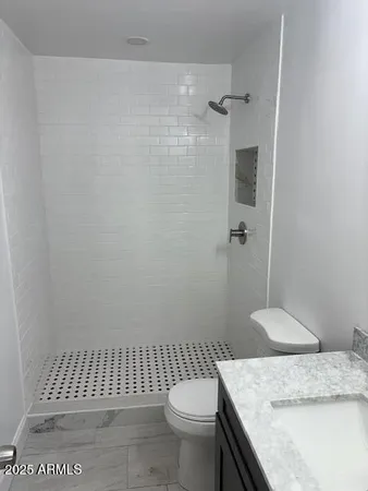 a bathroom with a granite countertop sink a toilet a shower and a mirror