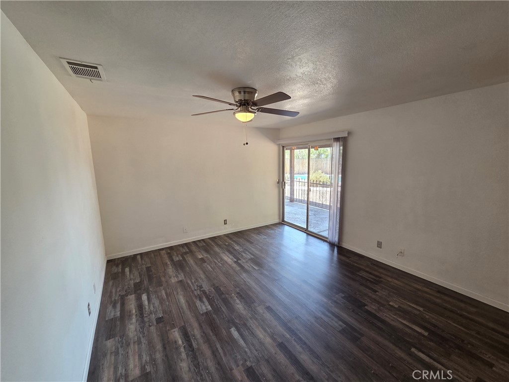 19145 Tomahawk Road Apple Valley, CA 92307 - Photo 19 of 38 an empty room with wooden floor and ceiling fan