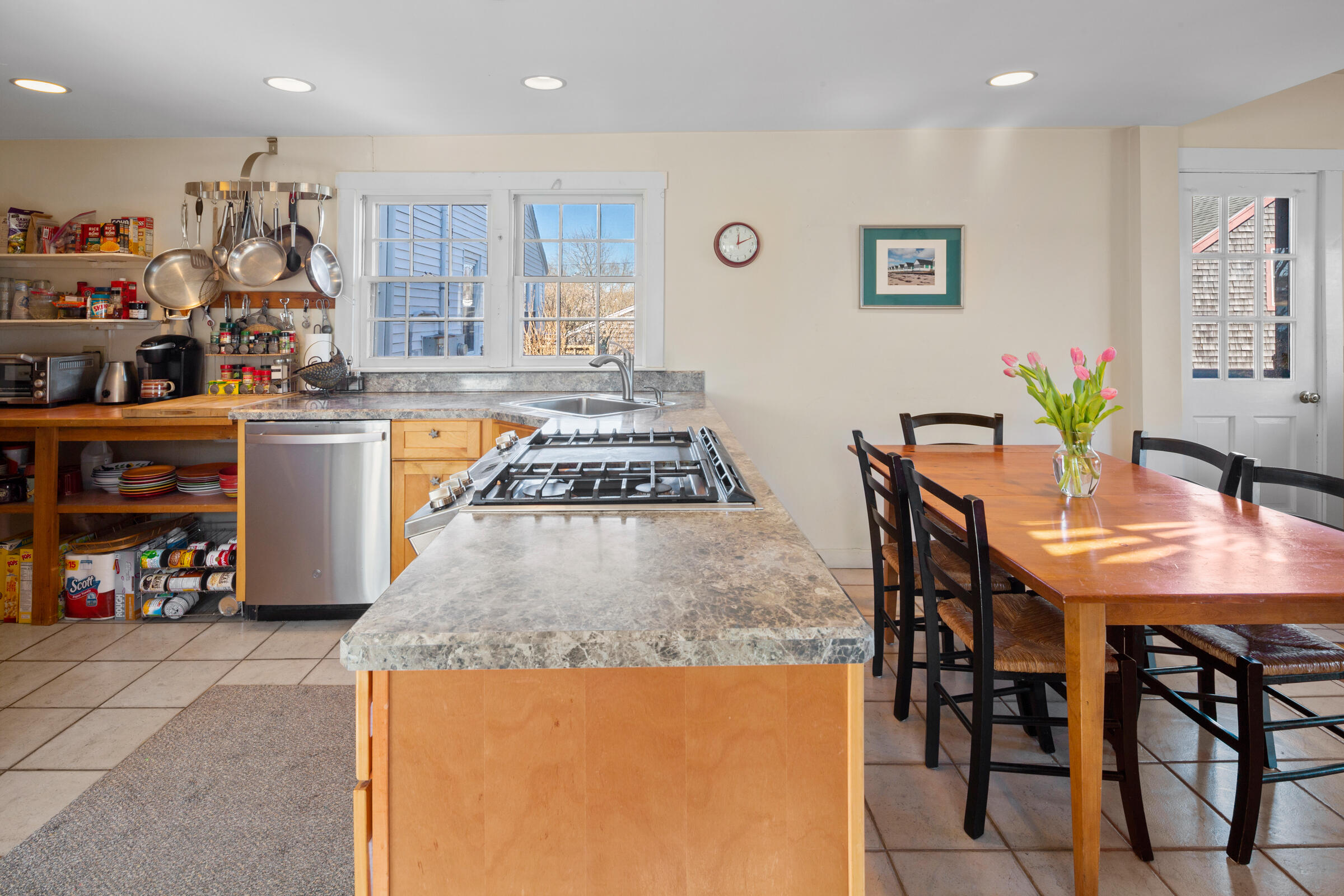 115 Commercial Street, Unit B Wellfleet, MA 02667 - Photo 11 of 37 a kitchen with stainless steel appliances granite countertop a table chairs and a refrigerator