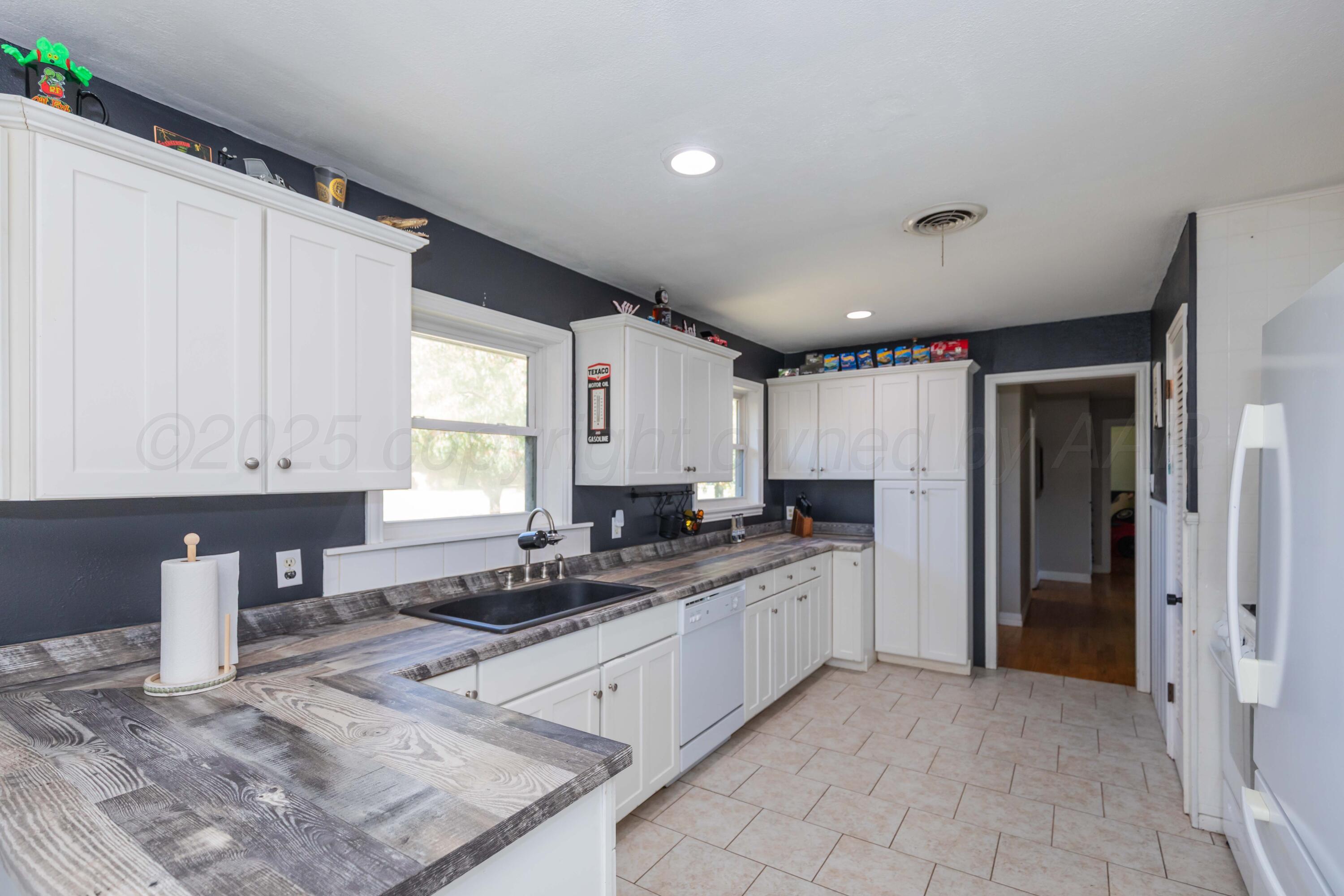 315 Pratt Street Claude, TX 79019 - Photo 14 of 38 a kitchen with granite countertop a sink stainless steel appliances white cabinets and a window