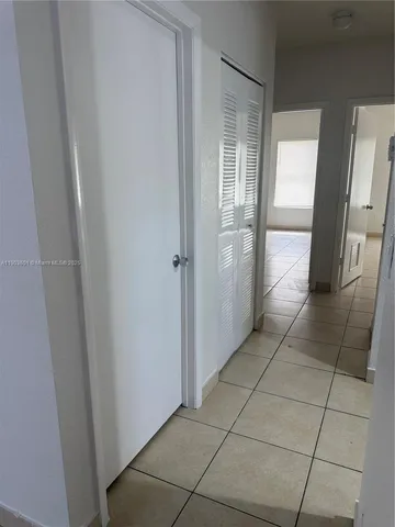 a view of a refrigerator in kitchen and an empty room in wooden floor