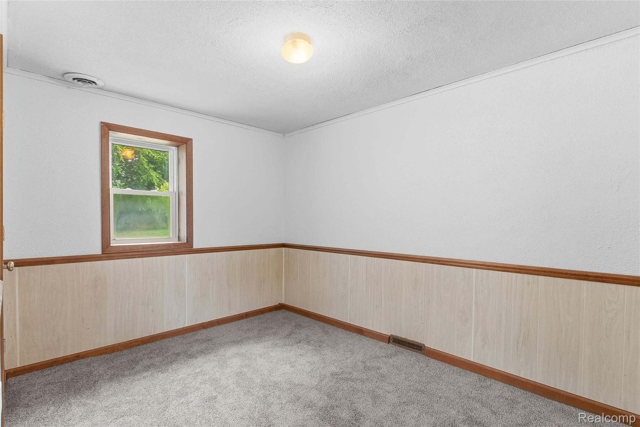 1843 Curtis Road Birch Run, MI 48415 - Photo 13 of 25 Carpeted room featuring a single window with wood trim, wood-paneled wainscoting, and a ceiling-mounted light fixture