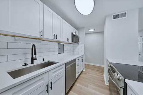 a kitchen with stainless steel appliances a sink a stove and a wooden floors