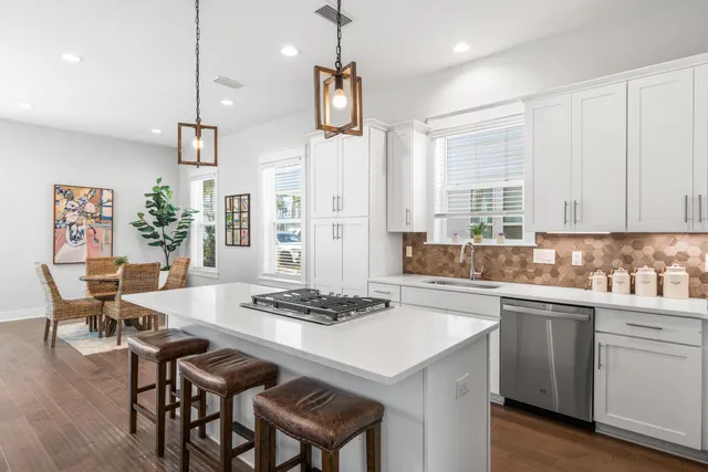 a kitchen with stainless steel appliances kitchen island a table chairs in it and white cabinets