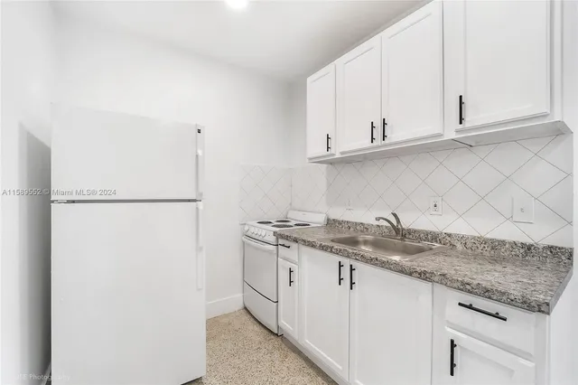 a kitchen with granite countertop white cabinets and a sink