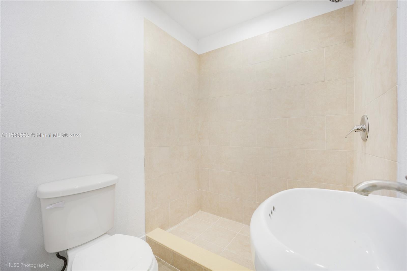 2130 Northwest 28th Street Miami, FL 33142 - Photo 7 of 48 a white toilet sitting next to a white sink and vanity