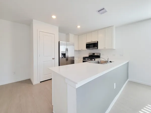 a kitchen with a sink a refrigerator and a stove top oven with wooden floor