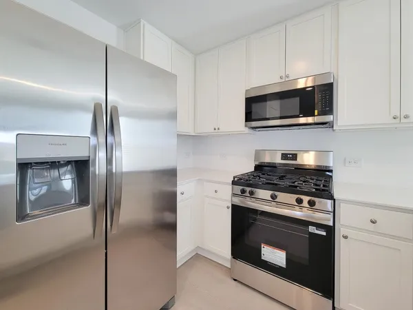 a kitchen with stainless steel appliances white cabinets and a stove top oven