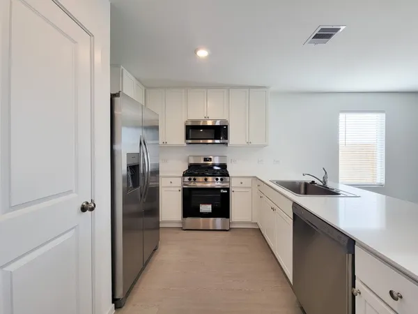 a kitchen with granite countertop white cabinets and stainless steel appliances