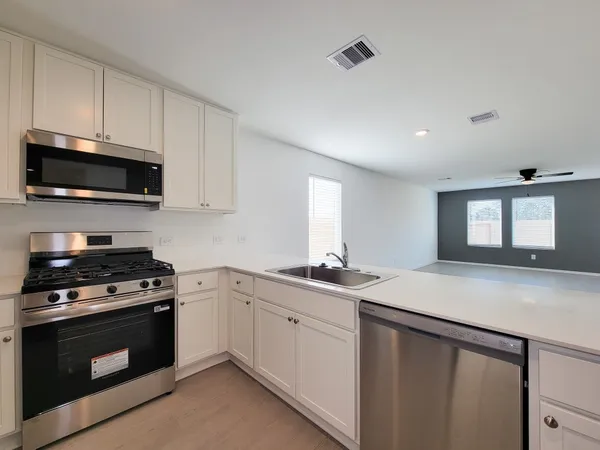 a kitchen with stainless steel appliances granite countertop a sink a stove a microwave and wooden cabinets