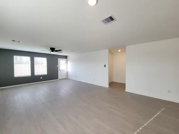 an empty room with wooden floor and windows