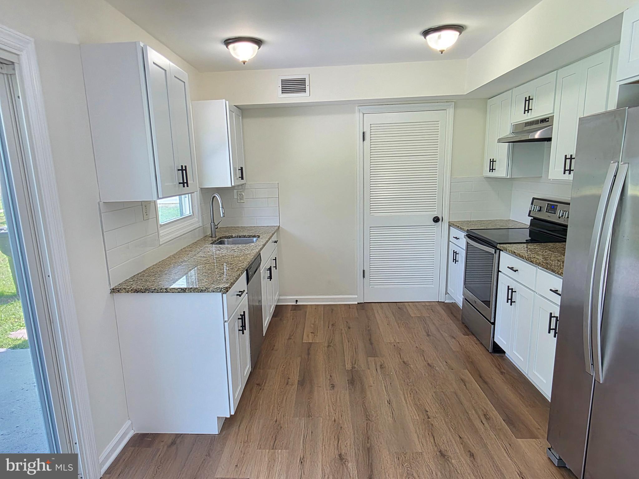 11 Guild Court Willingboro, NJ 08046 - Photo 9 of 16 a kitchen with stainless steel appliances granite countertop a refrigerator a stove a sink and white cabinets with wooden floor